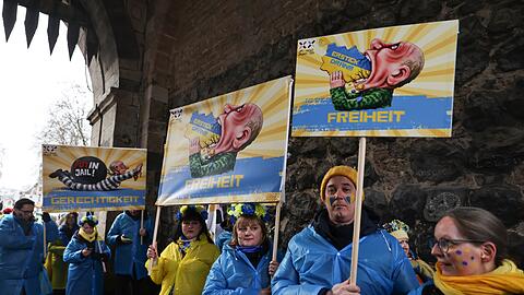 Mitglieder des ukrainischen Hilfsvereins Blau-Gelbes Kreuz halten im K&ouml;lner Rosenmontagszug Plakate mit fr&uuml;heren Putin-Darstellungen aus den Z&uuml;gen in K&ouml;ln und D&uuml;sseldorf hoch.