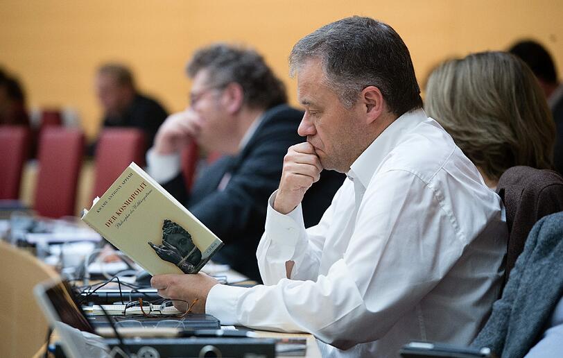 Der Landtagsabgeordnete Harald Kühn packt während der Sitzung ein Buch aus.