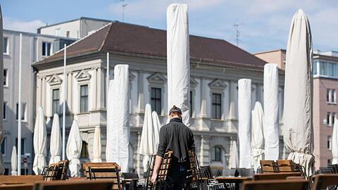 Ein Mann trägt Stühle auf den Rathausplatz in Augsburg. Foto: Tom Weller/dpa/Archivbild