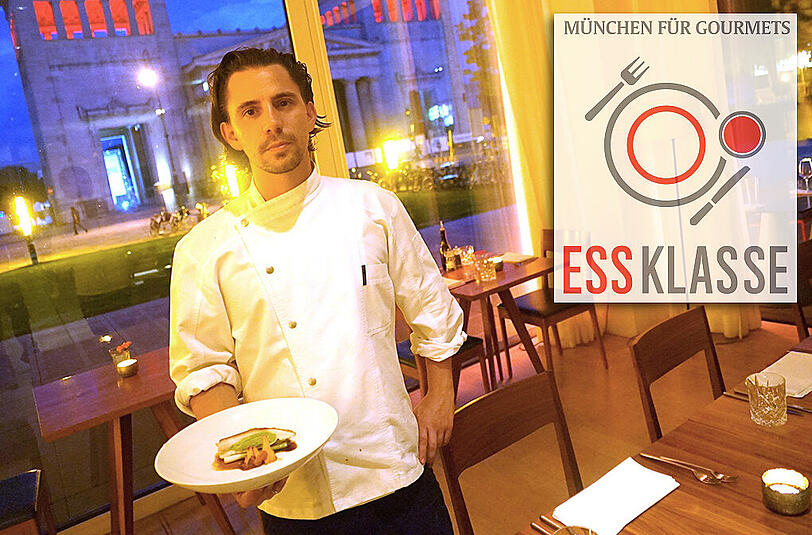 Küchenchef Michael Hausberger präsentiert im Restaurant Ella am Königsplatz den Hauptgang: Schwarzfederhuhn mit Erbse, Pfifferlingen und jungem Lauch &ndash; und draußen im Hintergrund grüßen die Propyläen.