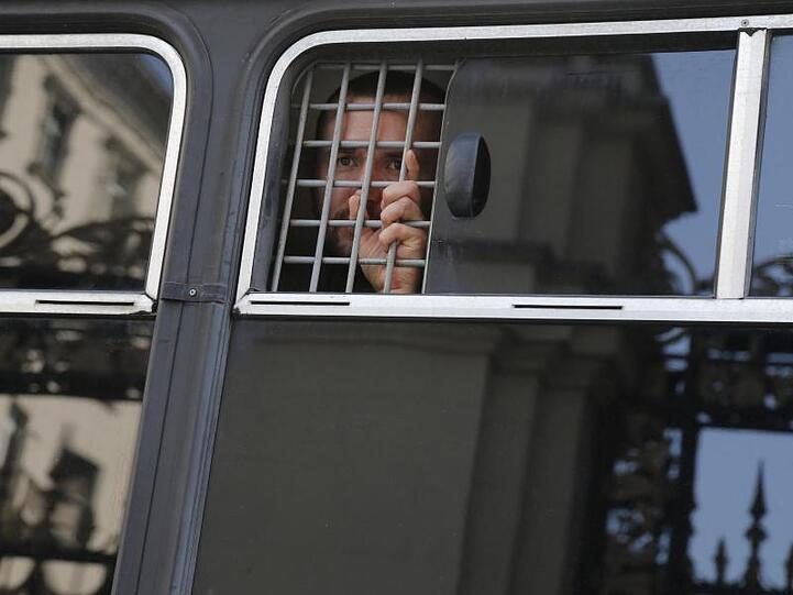 Ein Demonstrant wird in einem Polizeibus festgehalten.