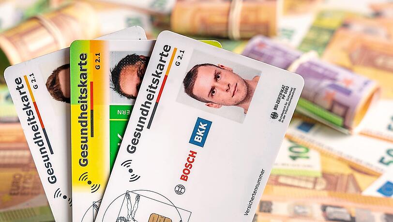 Hinter verschiedenen Gesundheitskarten liegen Geldscheine und B&uuml;ndel.