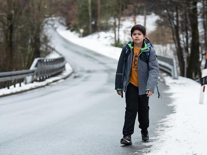 Marc läuft eine kurvige Landstraße entlang. Der Junge muss rund zwei Kilometer zu Fuß zur Haltestelle seines Schulbusses laufen.