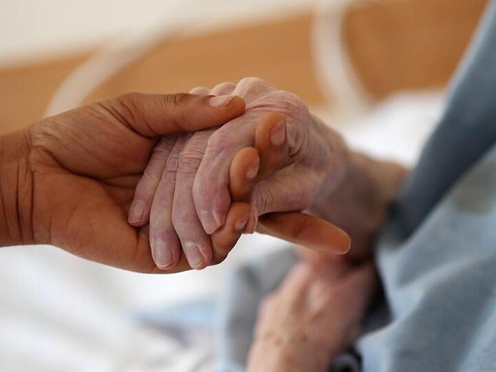 Eine Pflegerin hält im Altenheim die Hand einer Bewohnerin. Foto: Oliver Berg/dpa/Symbolbild