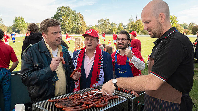 "Leberkäsjunkie": Die Fans von Rot-Weiß Niederkaltenkirchen stehen Schlange, um bei Metzger Simmerl (Stephan Zinner, r.) eine Wurst zu ergattern, auch Dorfpolizist Franz Eberhofer (Sebastian Bezzel, l.).