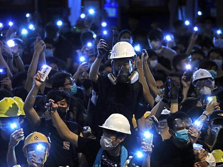 Demonstranten leuchten mit dem Licht ihre Handys vor dem Polizeipräsidium von Hongkong.
