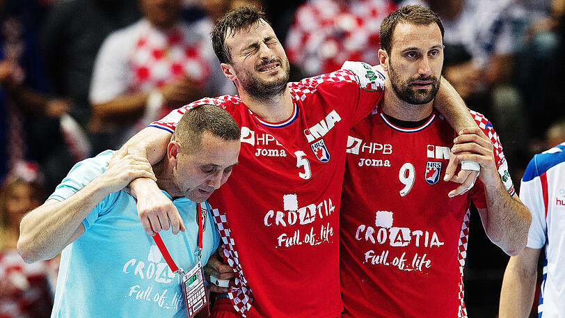 Kroatiens verletzter Spieler Domagoj Duvnjak (Mitte) wird von seinem Teamkollegen Igor Vori (rechts) vom Platz begleitet.