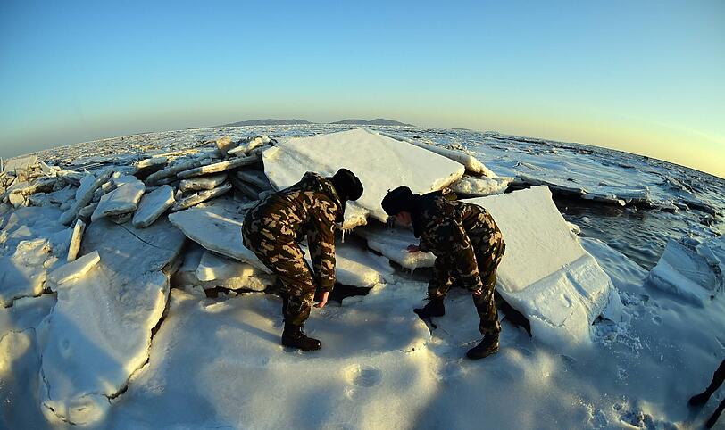 In China inspizieren Soldaten Eisschollen auf einem See.