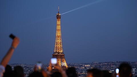 Paris im Sommer 2024 - besonders beliebt: Touristen fotografieren den Eiffelturm mit den Olympischen Ringen von der Terrasse des Triumphbogens. (Archivbild)