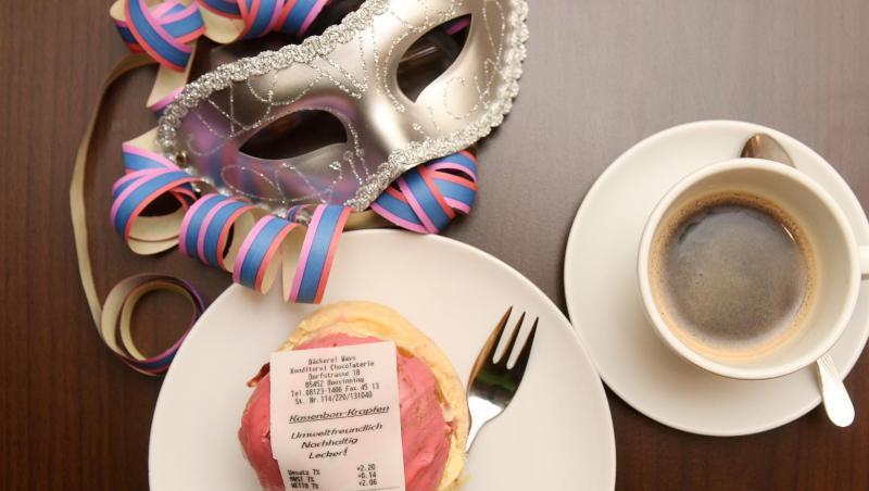 Ein Krapfen mit einem Kassenbon aus Fondant, einer essbaren Zuckermasse und eine Tasse Kaffee. Foto: Tobias Hase/dpa Ein Krapfen mit einem Kassenbon aus Fondant, einer essbaren Zuckermasse und eine Tasse Kaffee. Foto: Tobias Hase/dpa