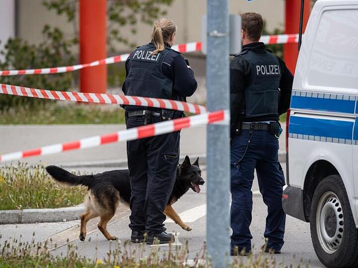 Zwei Polizisten mit einem Sprengstoff-Spürhund stehen vor dem Einkaufszentrum HEP in Holzkirchen. Foto: Lino Mirgeler