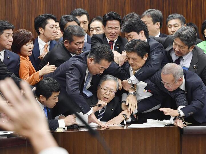 Handgemenge im japanischen Parlament: Mitglieder der Regierungspartei und der Opposition kämpfen in der Zuwanderungsdebatte um ein Mikrofon.