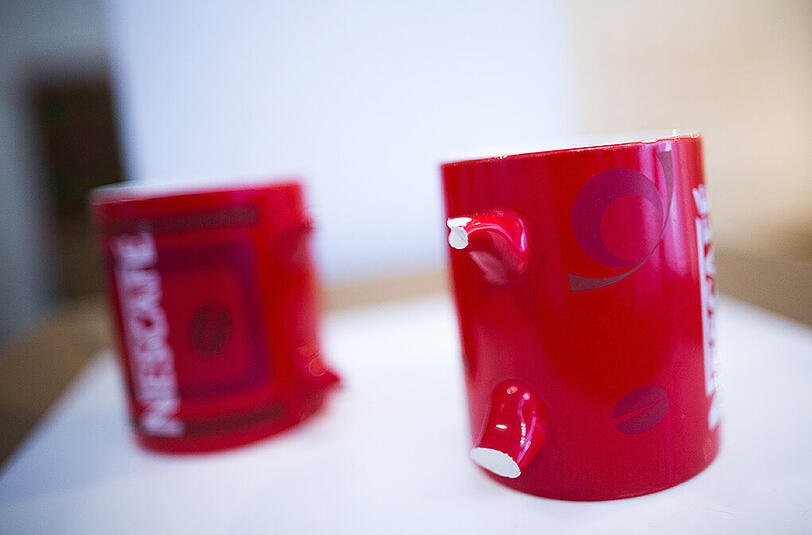 Zwei rote Kaffeetassen mit abgebrochenen Henkeln.