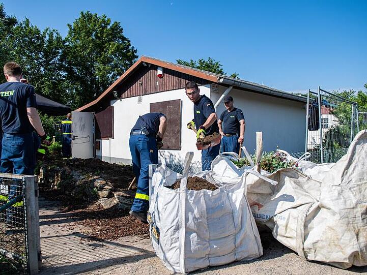 Mitarbeiter vom Technischen Hilfswerk (THW) tragen vor dem Abriss der Gartenlaube des Verdächtigen im Missbrauchsfall von Münster mit Schaufeln einen Erdhügel ab.