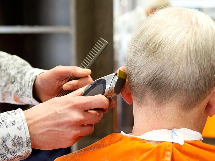 Ein Friseur schneidet einem Kunden die Haare. Foto: picture alliance/dpa/Archivbild