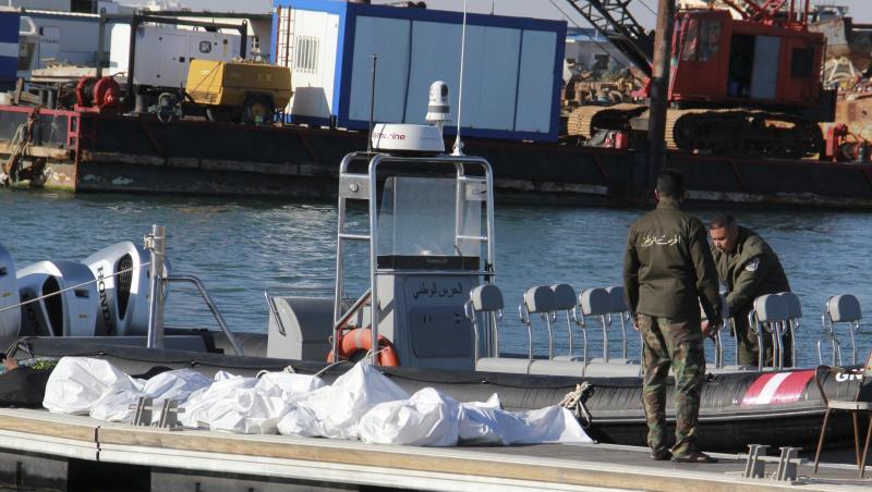 Einsatzkräfte der tunesischen Küstenwache im Hafen von Sfax neben zugedeckten Leichen auf einem Steg.