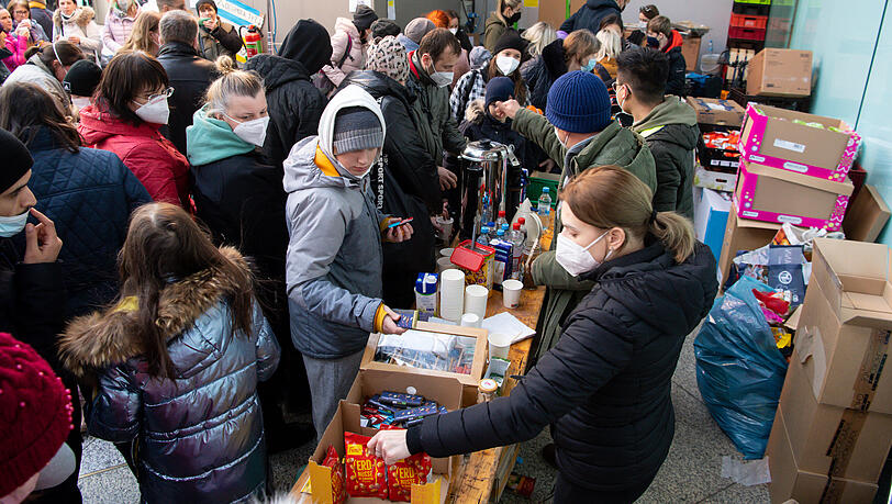 Flüchtlinge aus der Ukraine werden nach ihrer Ankunft am Münchner Hauptbahnhof von Mitarbeitern der Caritas und freiwilligen Helfern mit Lebensmitteln und Getränken versorgt.