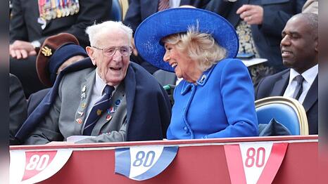 Königin Camilla amüsiert sich mit ihrem Sitznachbarn, dem 101 Jahre alten Veteranen Jack Mortimer.