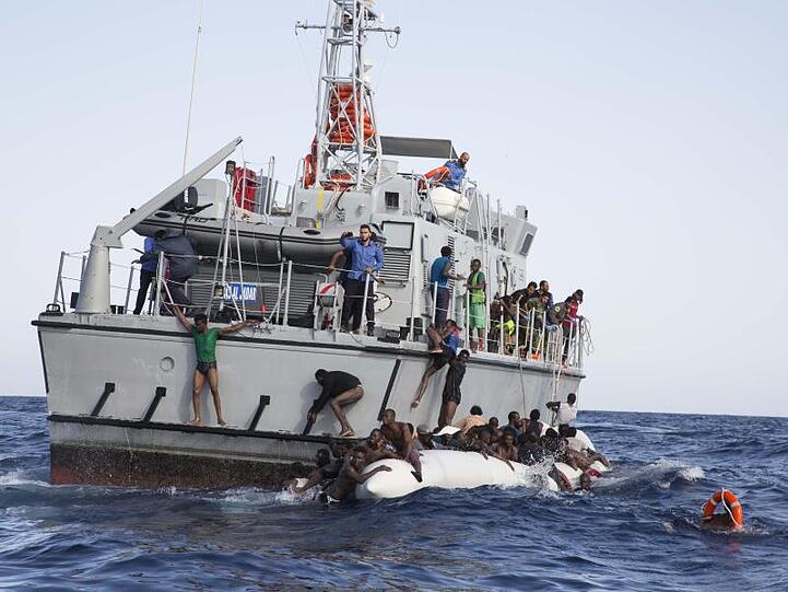 Libysche Flüchtlinge versuchen, an Bord eines Schiffs der libyschen Küstenwache zu gelangen.