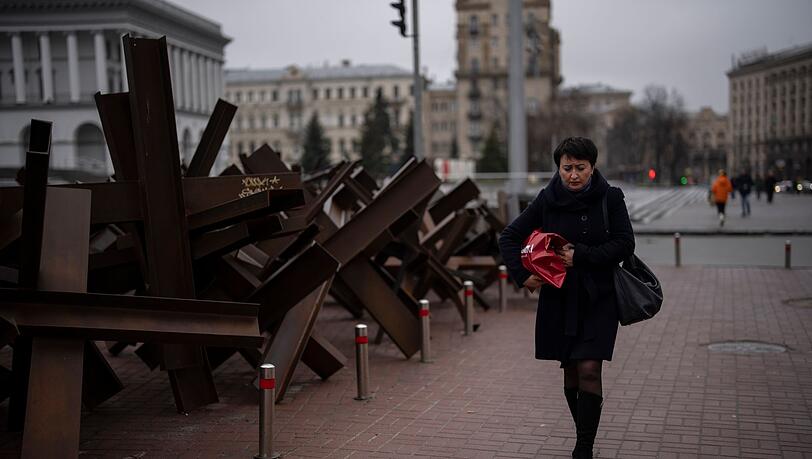 Eine Frau geht in Kiew an Panzersperren vorbei.