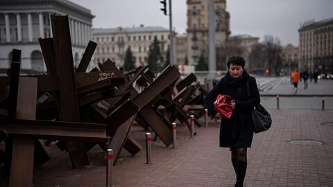 Eine Frau geht in Kiew an Panzersperren vorbei.