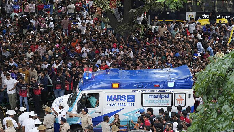 Ein Krankenwagen bahnt sich den Weg durch eine Menschenmenge am M. Chinnaswamy-Stadion in der indischen Stadt Bengaluru.