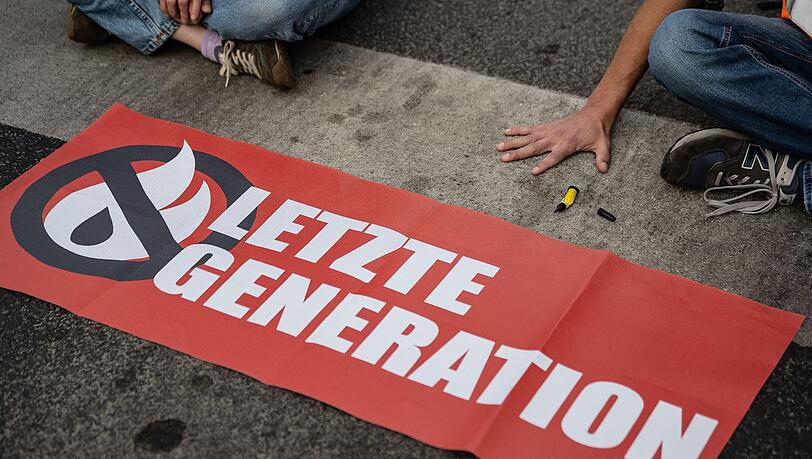 Ein Aktivist der Gruppe Letzte Generation hat sich auf eine Straße festgeklebt und blockiert eine Kreuzung. (Symbolbild)