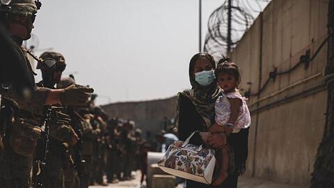 Marinesoldaten führen eine Frau, die ein Kind auf dem Arm trägt, während einer Evakuierung am Flughafen in Kabul.