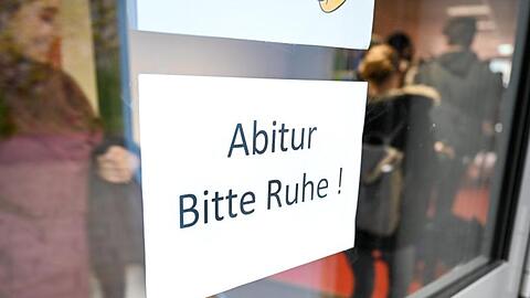 Abiturienten gehen kurz vor Beginn des Abiturs im Fach Deutsch zu ihrem Prüfungsraum an einem Schild vorbei. Foto: Felix Kästle/Archiv