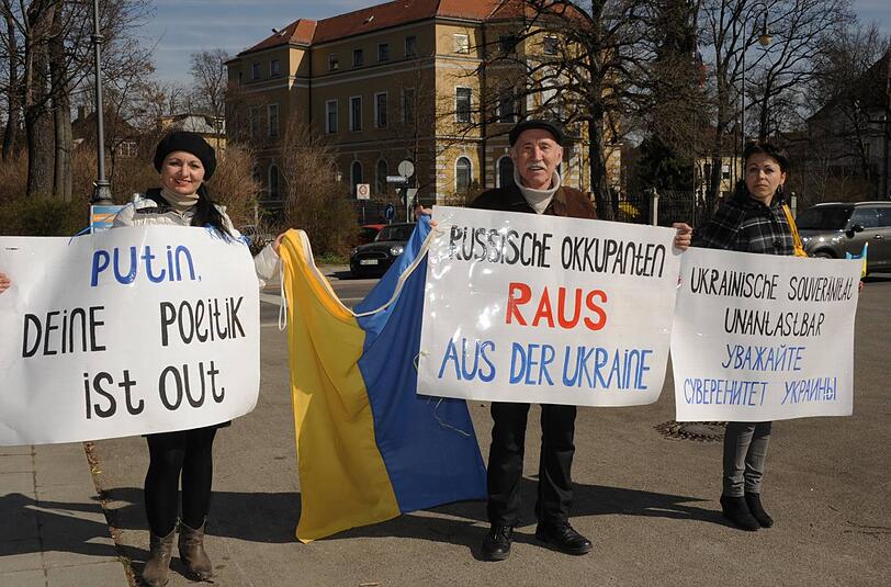Elvira Zechalo, Volodimir Stememko und Iryna Kulyk (v.li.) zeigen am Europaplatz ihre Protest-Plakate.