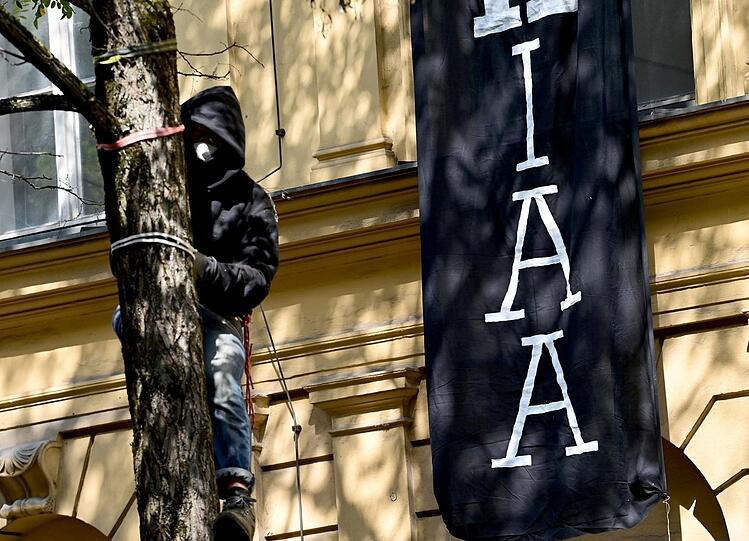 Ein Protestteilnehmer ist vor dem besetzten Haus auf einen Baum geklettert.