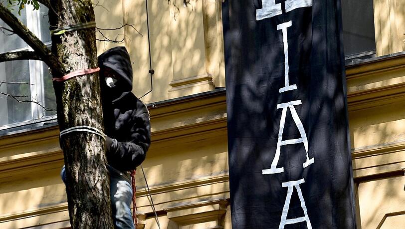Ein Protestteilnehmer ist vor dem besetzten Haus auf einen Baum geklettert. Ein Protestteilnehmer ist vor dem besetzten Haus auf einen Baum geklettert.