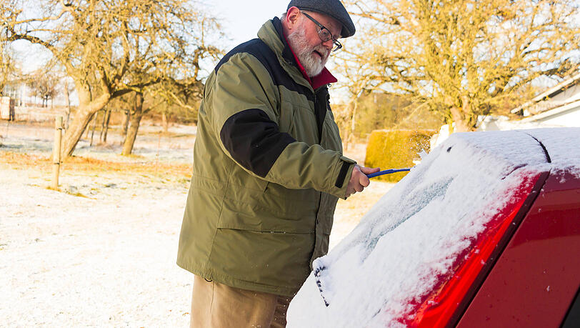 Ein Mann befreit seinen Wagen vom Schnee. Auch das Dach und die Motorhaube müssen freigeräumt sein. Ein Mann befreit seinen Wagen vom Schnee. Auch das Dach und die Motorhaube müssen freigeräumt sein.