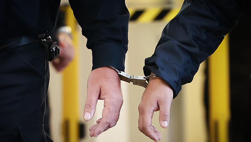Zwei Männer sind mit Handschellen aneinander gefesselt (Symbolbild)