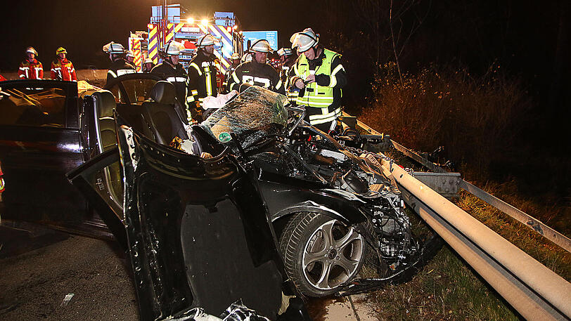 Feuerwehrleute stehen am 24.11.2017 auf der Autobahn 8 bei Leipheim (Bayern) hinter einem zerstörten Fahrzeug.