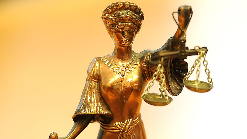 Eine goldfarbene Justitia-Figur mit verbundenen Augen und Waage in der Hand. (Symbolbild)