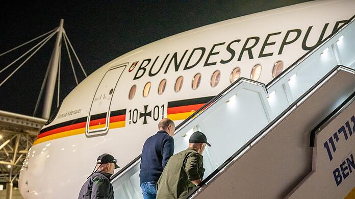 Bodyguards bringen Bundeskanzler Olaf Scholz nach dem Luftalarm in den Regierungs-Airbus.