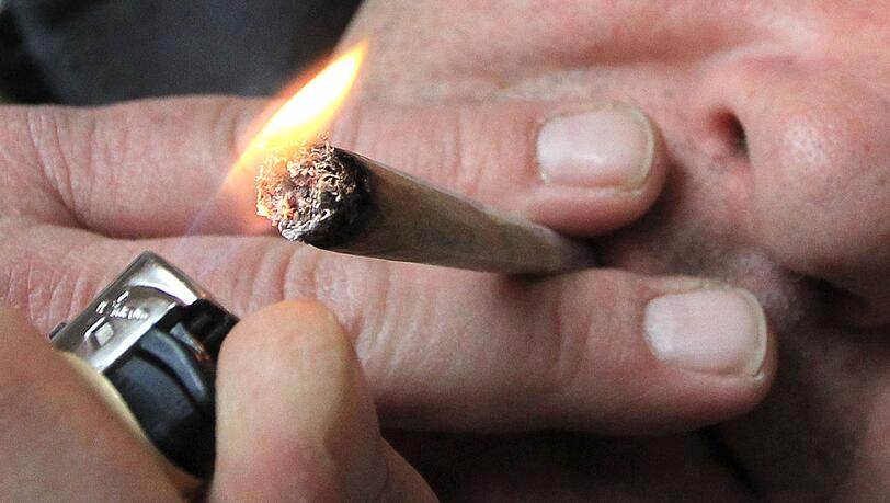 Ein Mann raucht eine selbst gedrehte Cannabis-Zigarette.