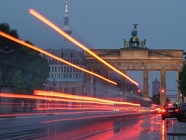 Durch eine Langzeitbelichtung sind die Rückleuchten eines Busses vor dem Brandenburger Tor als Linien zu sehen.