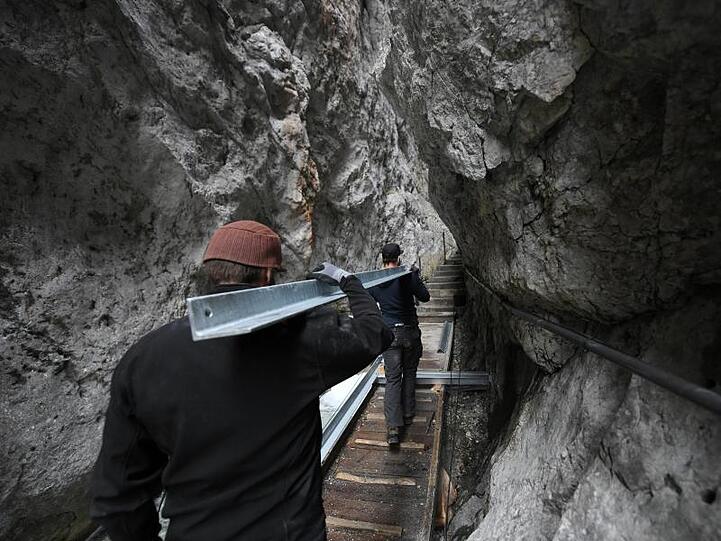 Ehrenamtlichen Helfer der DAV-Sektion Garmisch-Partenkirchen tragen einen Stahlträger in die Klamm. Foto: Angelika Warmuth/dpa