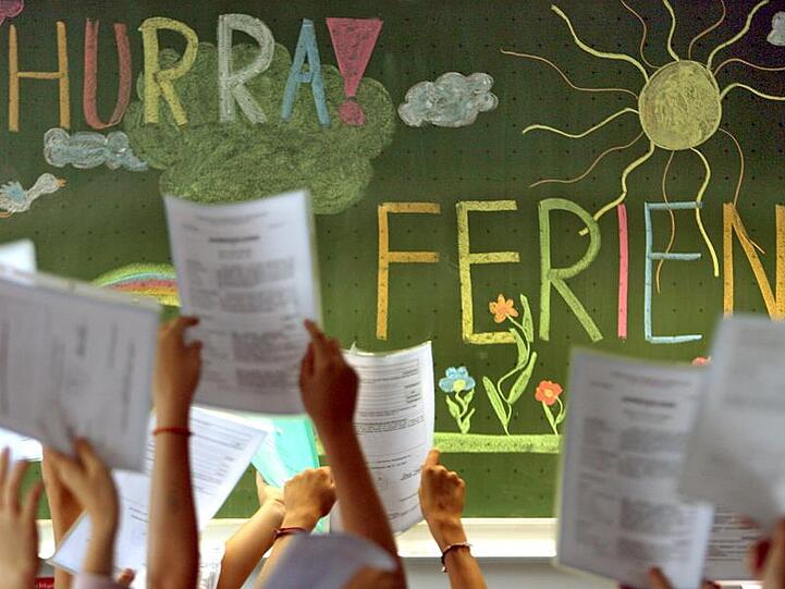 Kinder der vierten Klasse einer Grundschule in Kaufbeuren jubeln vor einer Tafel mit der Aufschrift "Hurra Ferien".