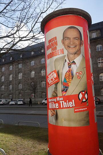 Für die wirbt der Sender jetzt mit einem Wahlplakat, auf dem Mike Thiel mit schriller Krawatte und Drei-Tage-bart zu sehen ist.