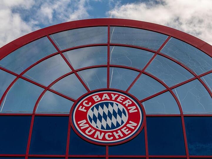 Das Logo des FC Bayern München hängt über der Einfahrt zum Gelände zum FC Bayern München. Foto: Peter Kneffel/dpa/Archivbild
