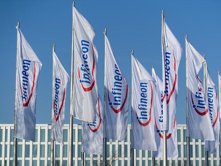 Flaggen mit dem Logo von Infineon flattern im Wind. Foto: Matthias Balk/Archivbild