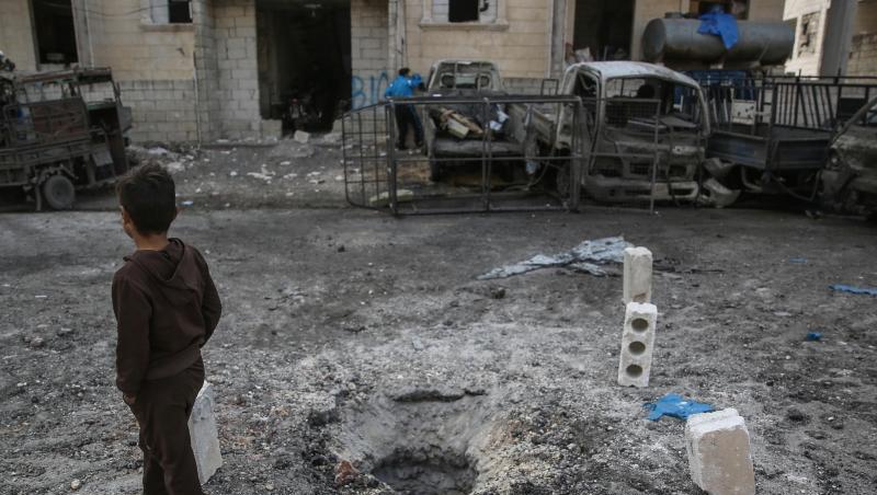 Ein Kind geht in Idlib nach einem Raketenbeschuss an einer Einschlagstelle im Boden vorbei. Ein Kind geht in Idlib nach einem Raketenbeschuss an einer Einschlagstelle im Boden vorbei.