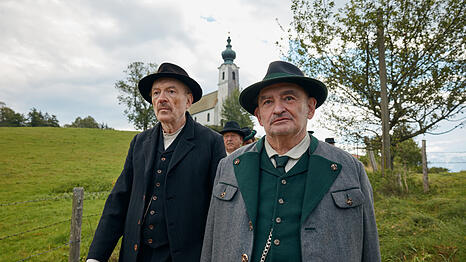 Schuster Julius Kraus (Josef Hader, l.) und Silvan Heingeiger (Sigi Zimmerschied, r.) gehen im Trauerzug für den verstorbenen Bürgermeister durchs Dorf.