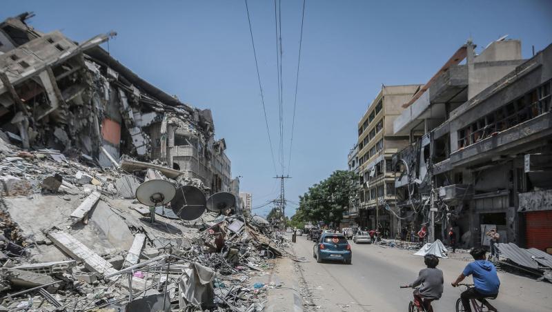 Palästinenser fahren an Gebäuden in Gaza vorbei, die durch israelische Luftangriffe zerstört wurden.