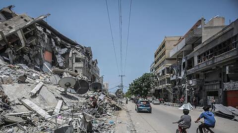 Palästinenser fahren an Gebäuden in Gaza vorbei, die durch israelische Luftangriffe zerstört wurden.