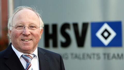 Club-Ikone Uwe Seeler lacht vor dem Logo des HSV.