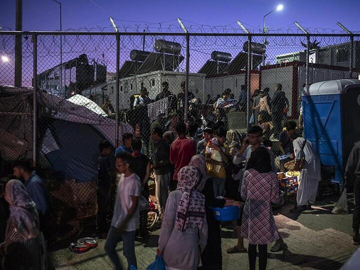 Migranten verlassen das Lager Moria aus Lesbos durch ein Loch im Zaun.
